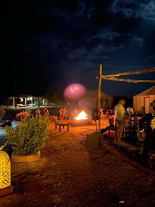 a group of people sitting around a fire at night at Tenere luxury camp in Merzouga