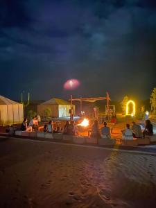 a group of people sitting around a pool at night at Tenere luxury camp in Merzouga