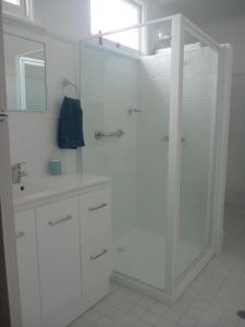 a white bathroom with a shower and a sink at Apartments On Grey in Glen Innes