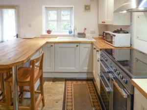 a kitchen with white cabinets and a wooden counter top at Bridge Cottage in Mitchel Troy