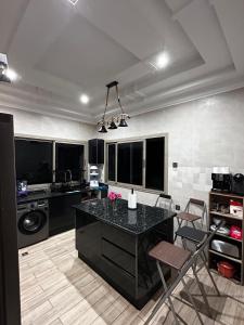 a kitchen with a black counter and chairs in it at Villa avec piscine in Meknès
