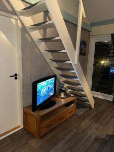 a tv sitting on a dresser next to a staircase at Ferienhaus in Stavenisse mit Garten, Whirlpool und gemeinsamem Pool in Stavenisse +14 photos
