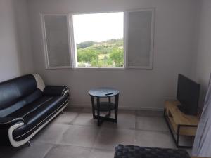 a living room with a couch and a table and a window at Le Mazet du Salagou in Clermont-lʼHérault