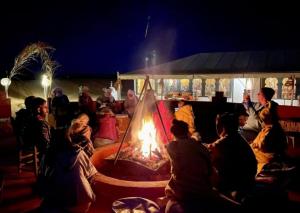 a group of people sitting around a fire at Erg Serenity Camp in Merzouga