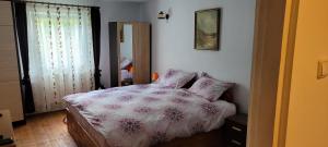 Schlafzimmer mit einem Bett mit einer rosa und weißen Bettdecke in der Unterkunft Casa Nadia in Voineasa