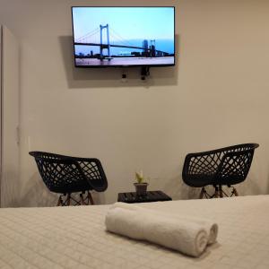 a room with a bed with two chairs and a tv on the wall at Apartamento Monoambiente en Encarnación con Parking in Encarnación