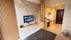 a bedroom with a tv on a marble wall at Sky House BSD Apartment - Leonie Tower by Betah Banget in Cilenggang