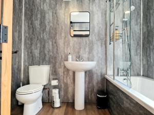 a bathroom with a toilet and a sink and a bath tub at Super Stylish and Vibrant 3 Bed Getaway in Hull