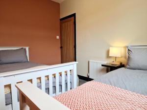 a bedroom with two beds and a door with a lamp at Super Stylish and Vibrant 3 Bed Getaway in Hull