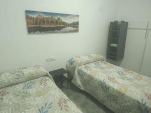 a room with two beds and a picture on the wall at Apartamentos Turísticos Atalaya in Minas de Ríotinto