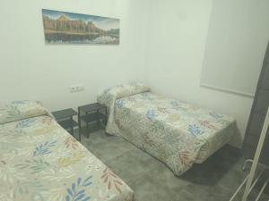 una stanza con due letti e un dipinto sul muro di Apartamentos Turísticos Atalaya a Minas de Ríotinto Altre 5 foto