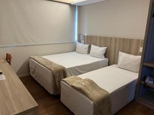 a room with two beds and a chair in it at Boa Vista Hotel in Oliveira