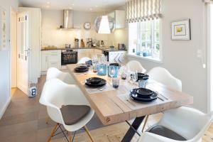 una sala da pranzo con un tavolo di legno e sedie bianche di Dünenzauber a List