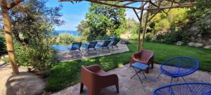 a patio with chairs and tables and a view of the water at Villa Acciagina 10 pers PISCINE VUE MER PINARELLO Climatisée in Pinarellu