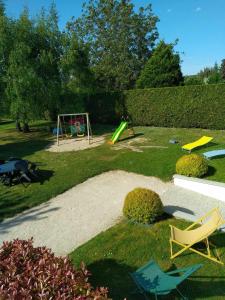un cortile con parco giochi, sedie e altalena di NOUVEAU - GÎTE DU MOULIN A VENT - Zoo à 10 mn - Jeux pour enfants a Noyers-sur-Cher