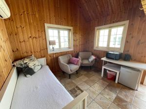 a room with a bed and two chairs in a cabin at Villa Krågenes - Hytte in Farsund