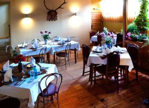 une salle à manger avec des tables blanches, des chaises et des fleurs dans l'établissement B&B Dumbrava, à Gura Humorului