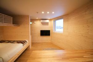 a bedroom with wooden walls and a bed with a window at Yotei View Tiny House in Kutchan