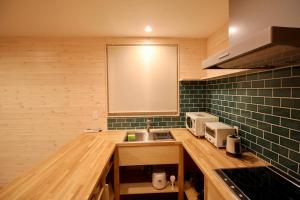 a kitchen with a sink and green tiled walls at Yotei View Tiny House in Kutchan +4 photos
