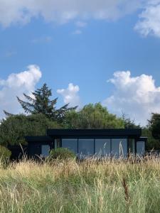 a black house on a hill in a field at First row - SUPER beach - best sunset view in Føllenslev