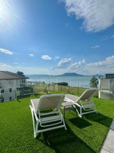 two lounge chairs sitting on a lawn with a view of the water at Villapark apartman A-B 12 in Fonyód