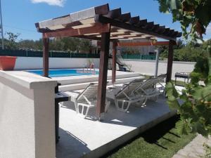a pergola and lounge chairs next to a pool at Bruna's apartment in Vrulje
