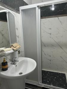 a white bathroom with a shower and a sink at Diamond Hotel in Chişinău