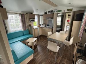a living room and kitchen with a blue couch and a table at Omaha beach mobilhome in Colleville-sur-Mer