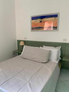 ein Bett in einem Schlafzimmer mit einem Gemälde an der Wand in der Unterkunft Vacanze in natura incontaminata "case vacanza Francesca-Gaia" in Isola Rossa