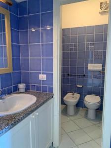 ein blau gefliestes Badezimmer mit Waschbecken und Toilette in der Unterkunft Vacanze in natura incontaminata "case vacanza Francesca-Gaia" in Isola Rossa