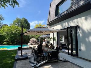a group of people sitting at a table under an umbrella at Casa de Leon Lakeview Guesthouse in Mississauga