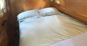 a small bed with white sheets and pillows at Daisy Mutler Holiday Boat Hire in Bletchley
