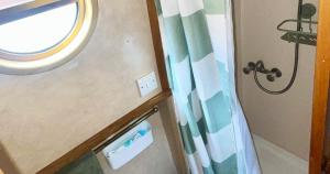 a bathroom with a window and a shower curtain at Daisy Mutler Holiday Boat Hire in Bletchley
