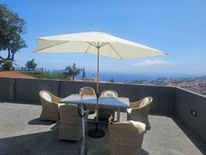 a table and chairs with an umbrella on a balcony at Ocean Paradise de Santa Luzia in Funchal