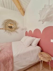 a bedroom with a pink and white bed and a table at La Rose des Sables suite 5 étoiles in Les Issambres