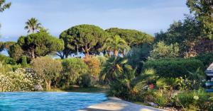 a garden with a swimming pool and trees at La Rose des Sables suite 5 étoiles villa Côté Cœur in Les Issambres