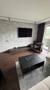 Ziogu Apartments في بالانغا: غرفة معيشة مع طاولة قهوة سوداء وتلفزيون بشاشة مسطحة +9 صور