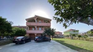two cars parked in front of a pink building at Asko Villa Apartment in Ulcinj