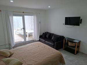 a bedroom with a bed and a couch and a television at Gramado in Cruz del Eje