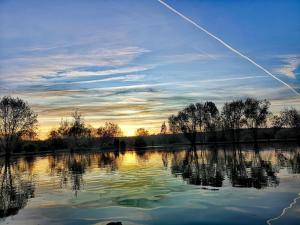 a view of a river at sunset with a plane at La roulotte de l'étang in Chessy-les-Prés