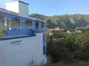 a blue and white building with mountains in the background at Djabraba's Trail in Vila Nova Sintra