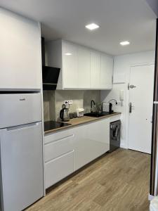 a white kitchen with white cabinets and a refrigerator at La Tropicale in Torrevieja
