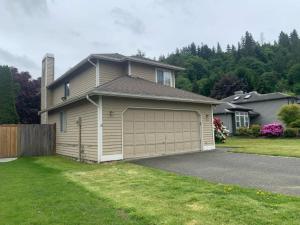 a house with a large garage in a yard at Cedar River one bedroom in a four bedroom house in Renton