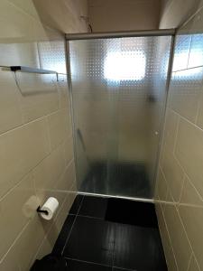 a shower with a glass door and a roll of toilet paper at Apto - Brasilândia do Sul - PR in Assis Chateaubriand