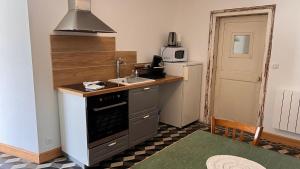 a small kitchen with a stove and a microwave at Chez Loulou - La suite in Lainsecq