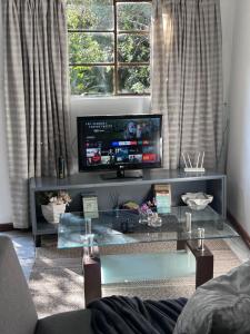 a living room with a tv and a glass table at Cozy Garden cottage in Roodepoort +4 photos