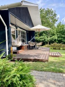 un patio con una mesa y una sombrilla en una casa en The forest cottage with petanque court, en Nykøbing Sjælland