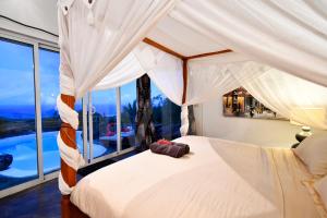 a bedroom with a canopy bed with a large window at Villa Lorizon in Rodrigues Island +74 photos