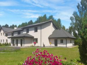 a white house with a green yard with flowers at Leśny Apartament I in Szczytno