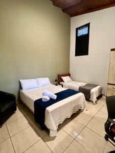 a room with two beds and a chair in it at Casa do Cerrado in Ribas do Rio Pardo +8 photos